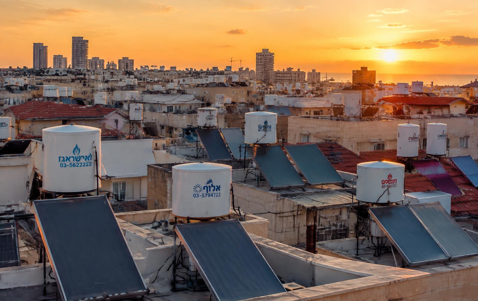 גגות עיר בישראל בשקיעה עם דודי שמש וקולטים